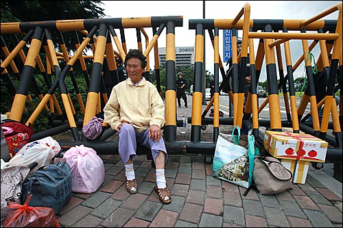 한 할머니가 아들에게 음식을 전하지 못 하게 되자 정문 바리케이드에 앉아 경찰의 조치에 항의하고 있다. 